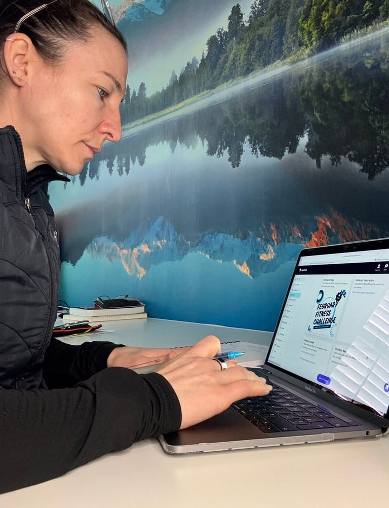 Woman working on laptop at desk with scenic mountain lake mural in background